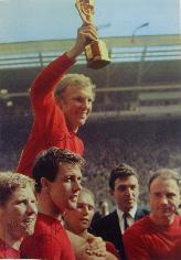 Bobby Moore celebrates with the Jules Rimet Trophy from magazine signed by Bobby Moore