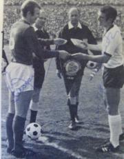 Signed Bobby Moore exchanging pennant with Uwe Seeler signed magazine picture